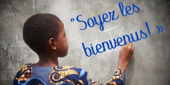 Un enfant écrit un message de bienvenue au tableau
